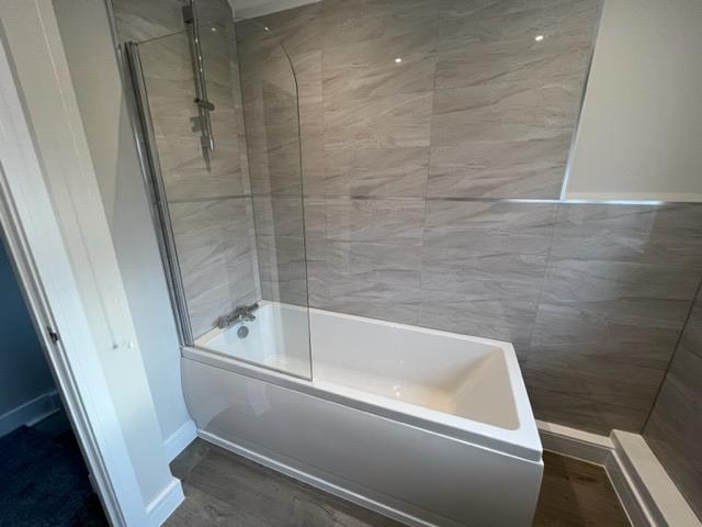 Clean modern bathroom with bath and shower screen